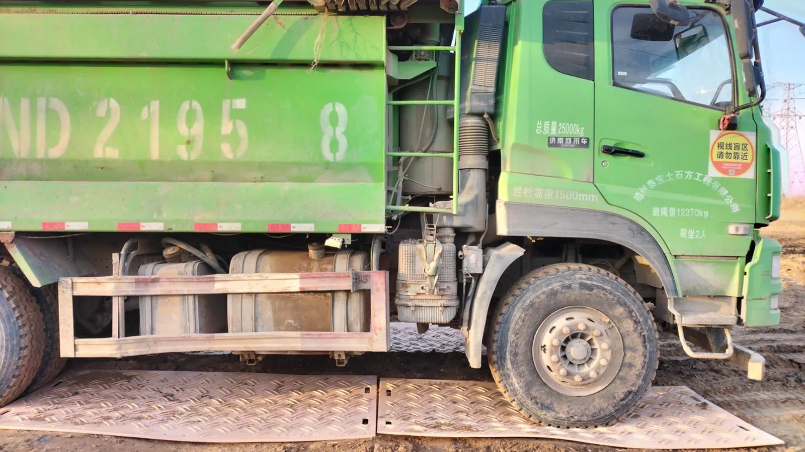 Tipper truck driving over temporary HDPE road mats on soft ground